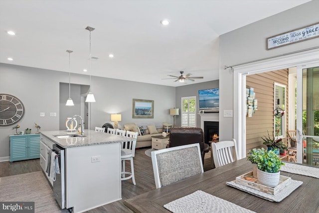 kitchen featuring sink, a center island with sink, decorative light fixtures, dark wood-type flooring, and a kitchen breakfast bar