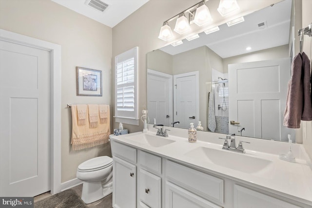 bathroom featuring vanity, a shower with shower door, and toilet