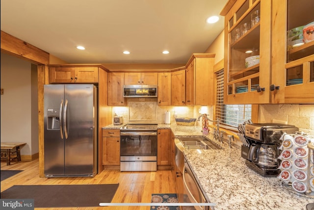 kitchen featuring light stone counters, sink, tasteful backsplash, stainless steel appliances, and light hardwood / wood-style floors