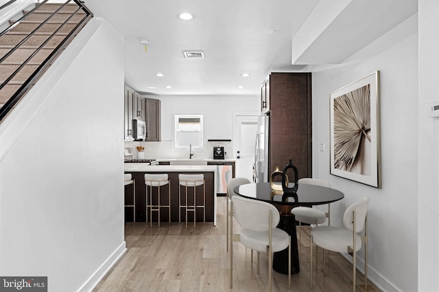 dining space with light wood-type flooring and sink