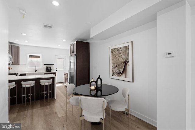 dining space with light wood-type flooring and sink