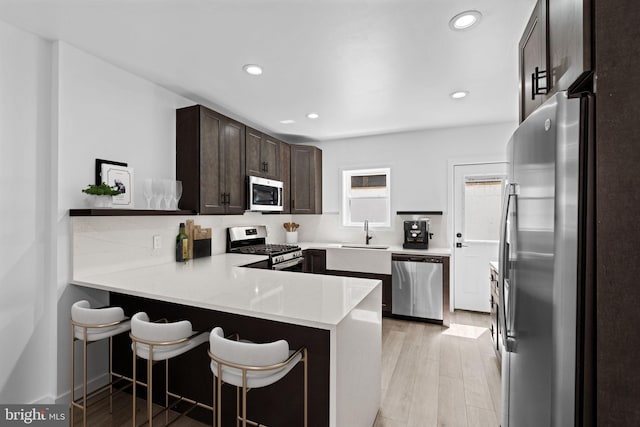 kitchen with a breakfast bar, stainless steel appliances, kitchen peninsula, and sink