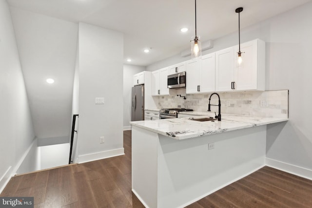 kitchen with kitchen peninsula, appliances with stainless steel finishes, sink, white cabinets, and hanging light fixtures