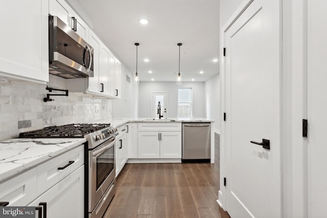 kitchen featuring white cabinets, appliances with stainless steel finishes, light stone countertops, and sink