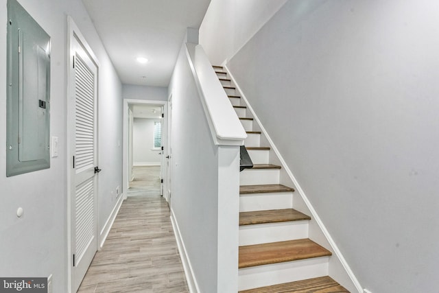 stairs with hardwood / wood-style flooring and electric panel