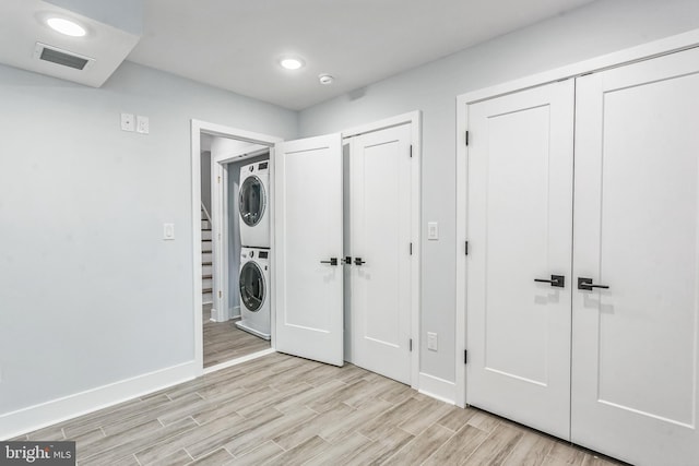 washroom featuring stacked washing maching and dryer and light hardwood / wood-style floors