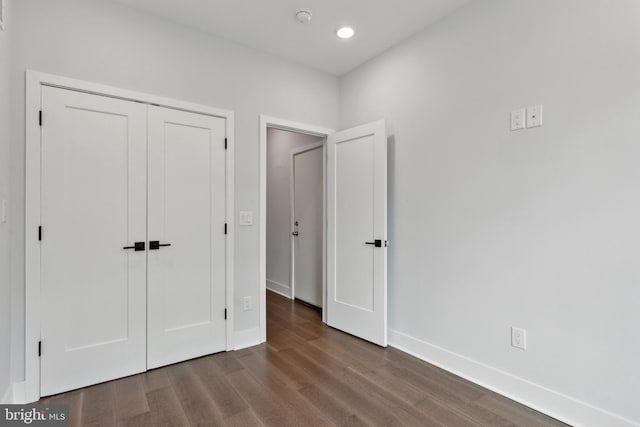 unfurnished bedroom with dark hardwood / wood-style flooring and a closet