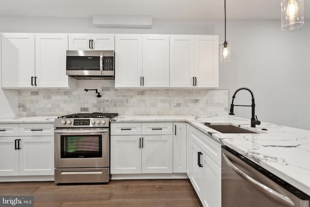 kitchen featuring sink, decorative backsplash, appliances with stainless steel finishes, decorative light fixtures, and white cabinetry