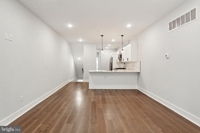 kitchen featuring hanging light fixtures, dark hardwood / wood-style flooring, kitchen peninsula, decorative backsplash, and white cabinets