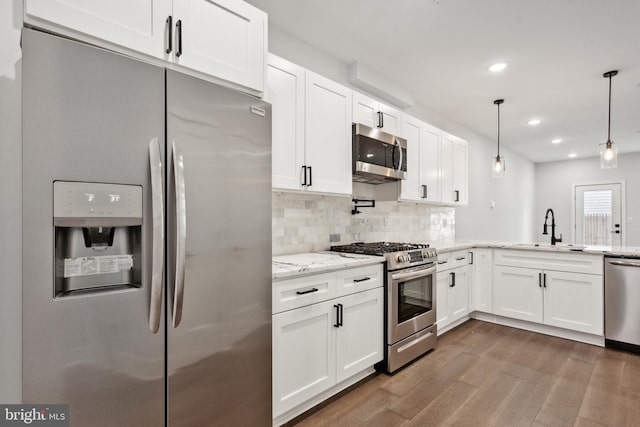 kitchen with white cabinetry, sink, stainless steel appliances, and decorative light fixtures