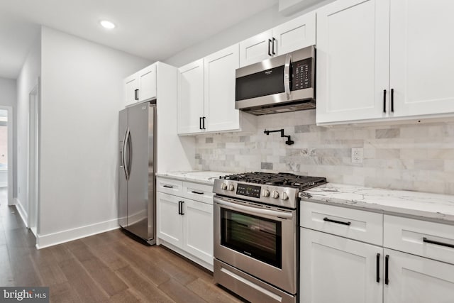 kitchen featuring light stone countertops, tasteful backsplash, stainless steel appliances, dark wood-type flooring, and white cabinetry