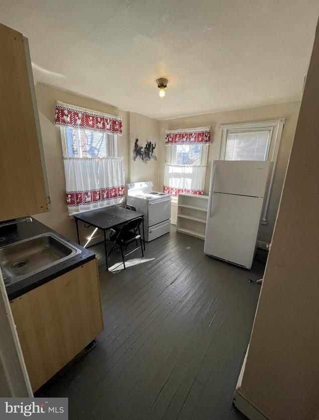 kitchen with white appliances, light brown cabinetry, and dark hardwood / wood-style floors