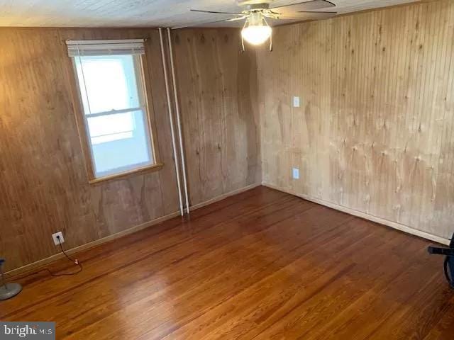 spare room with wood walls, ceiling fan, and hardwood / wood-style floors