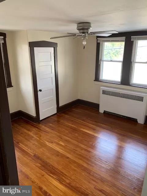 interior space featuring dark hardwood / wood-style floors, ceiling fan, and radiator heating unit