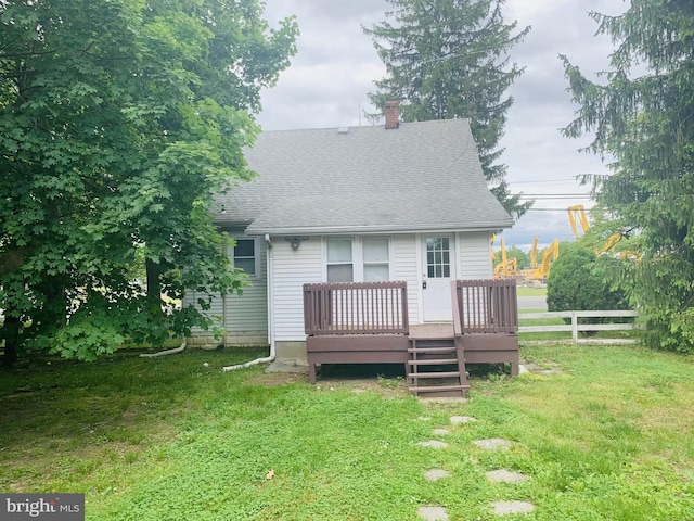 back of property with a wooden deck and a yard