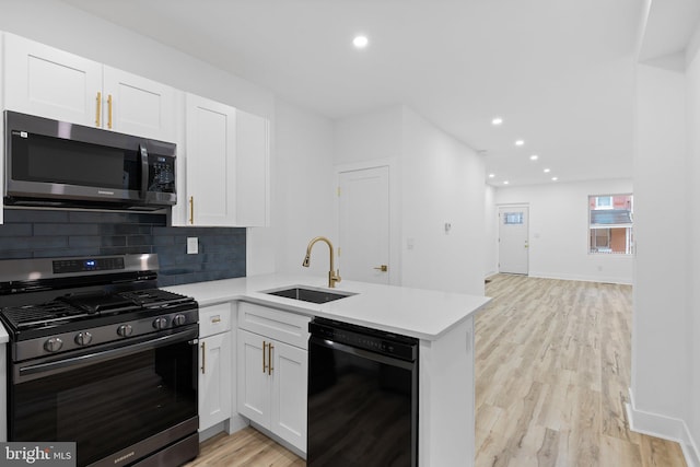 kitchen with appliances with stainless steel finishes, kitchen peninsula, white cabinetry, and sink