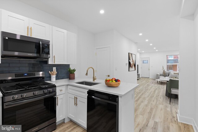 kitchen with kitchen peninsula, white cabinetry, sink, and stainless steel appliances