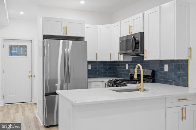 kitchen featuring light stone countertops, stainless steel appliances, white cabinetry, and light wood-type flooring