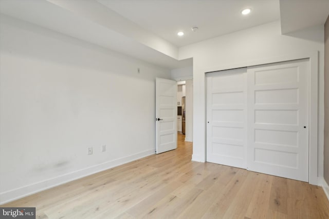 unfurnished bedroom with light wood-type flooring and a closet