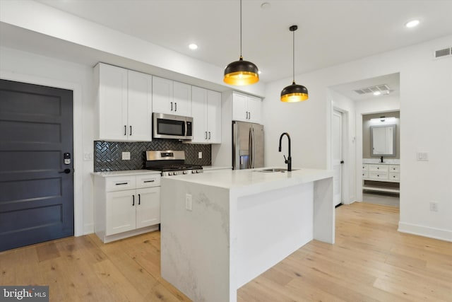 kitchen with pendant lighting, stainless steel appliances, white cabinetry, and sink