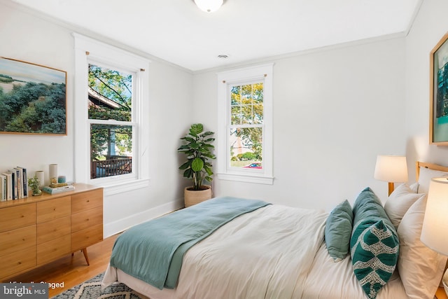 bedroom with hardwood / wood-style flooring, ornamental molding, and multiple windows