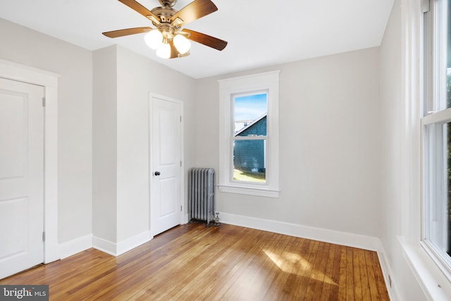 unfurnished bedroom with ceiling fan, light hardwood / wood-style flooring, and radiator heating unit