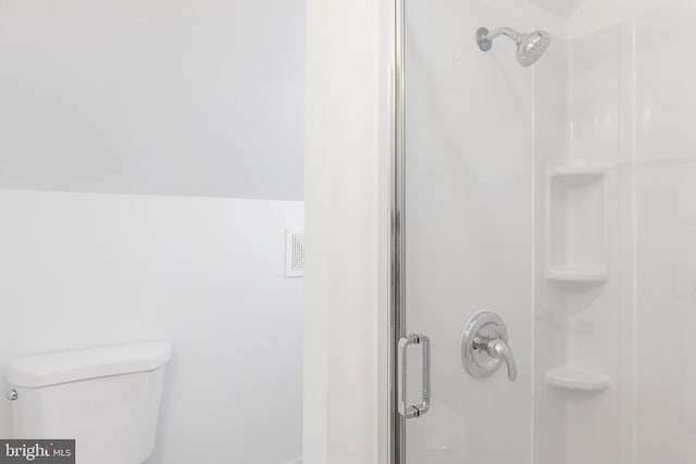 bathroom with toilet and a shower with shower door