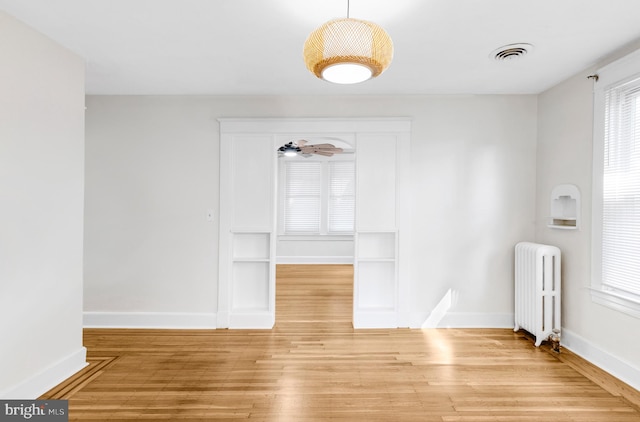 spare room featuring ceiling fan, radiator heating unit, and wood-type flooring