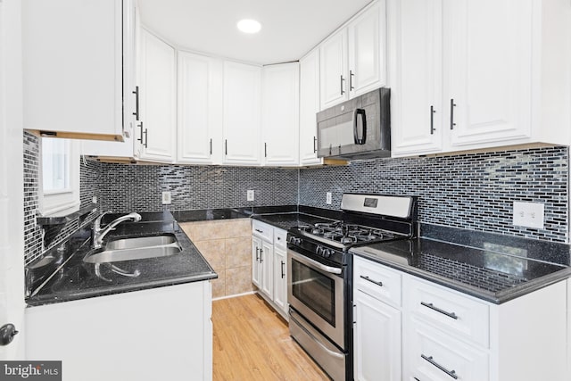 kitchen featuring light hardwood / wood-style flooring, stainless steel range with gas cooktop, sink, and white cabinets