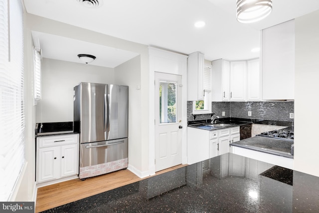 kitchen with light hardwood / wood-style floors, dark stone countertops, white cabinetry, and stainless steel appliances