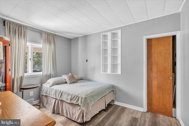 bedroom with hardwood / wood-style flooring and wooden walls