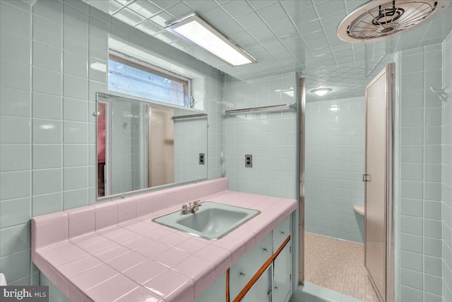 bathroom featuring vanity, tile patterned floors, a shower with shower door, and tile walls