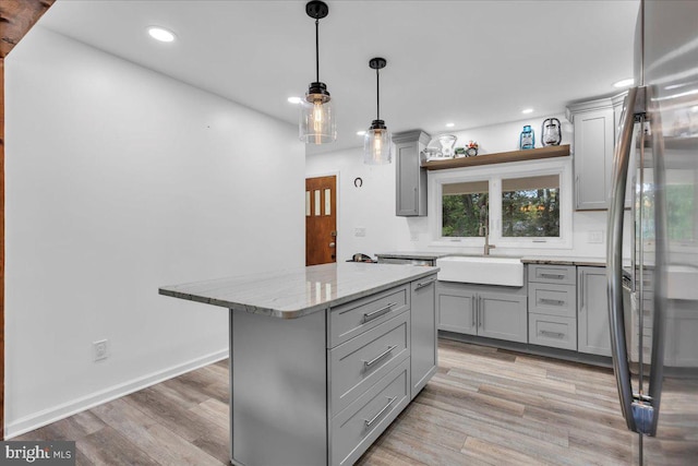 kitchen with stainless steel fridge, a kitchen island, light hardwood / wood-style flooring, gray cabinets, and sink