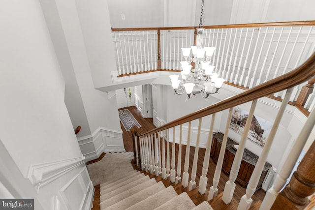 staircase with wood-type flooring and a chandelier