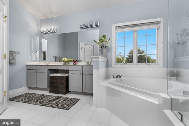 bathroom with tiled bath, vanity, and tile patterned floors