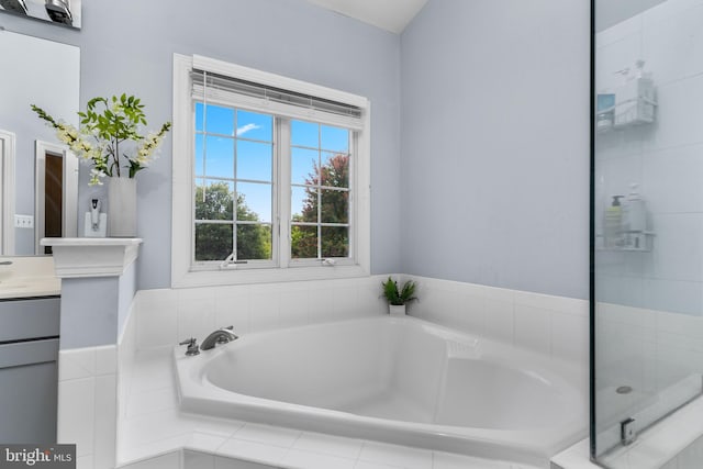 bathroom with a relaxing tiled tub and vanity