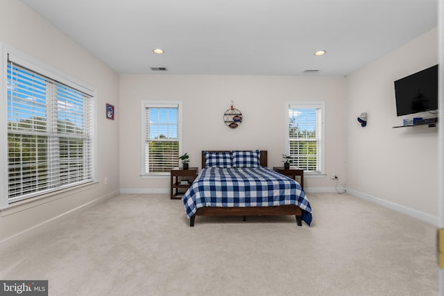 bedroom featuring light carpet and multiple windows