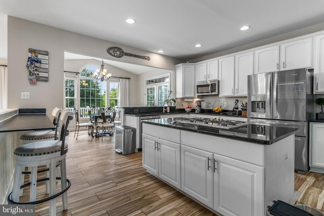 kitchen featuring light wood-type flooring, a chandelier, stainless steel appliances, and white cabinets