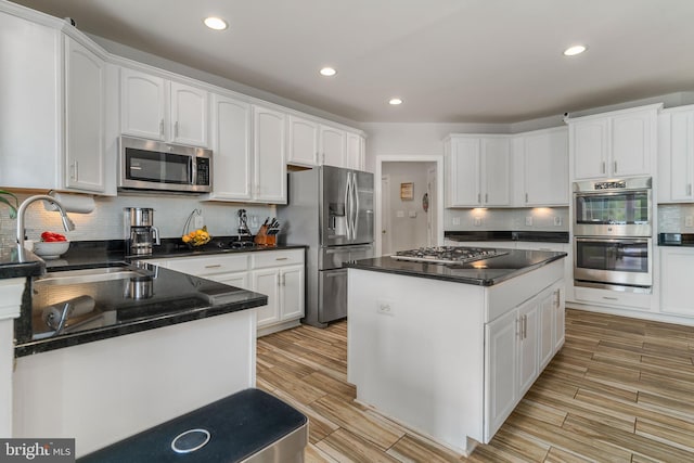 kitchen with light wood-type flooring, a center island, sink, white cabinetry, and appliances with stainless steel finishes