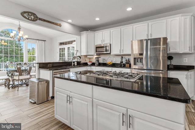 kitchen featuring a chandelier, a center island, white cabinetry, vaulted ceiling, and stainless steel appliances