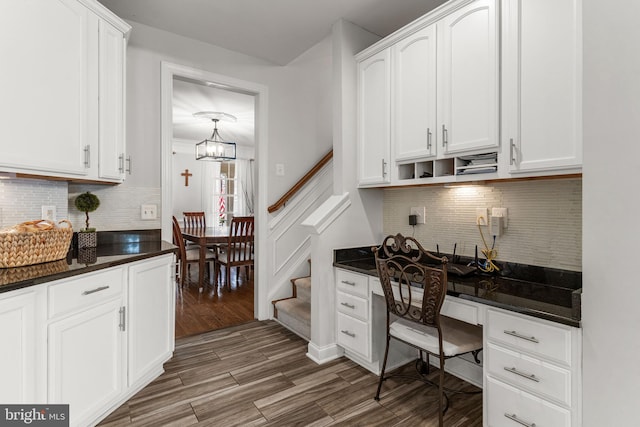 kitchen with built in desk, white cabinetry, dark wood-type flooring, and a chandelier