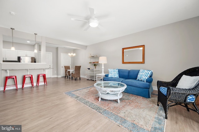 living room with ceiling fan with notable chandelier and light wood-type flooring