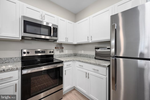 kitchen with appliances with stainless steel finishes, white cabinetry, and light stone counters