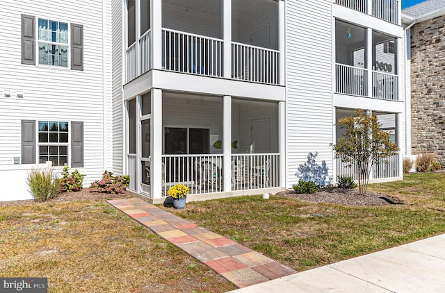 view of side of property with a lawn and a balcony