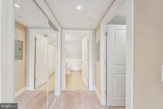 hallway with light colored carpet and electric panel