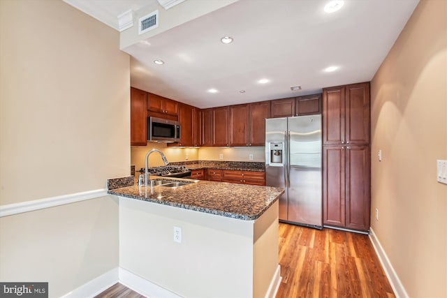 kitchen with dark stone counters, kitchen peninsula, light hardwood / wood-style flooring, and stainless steel appliances