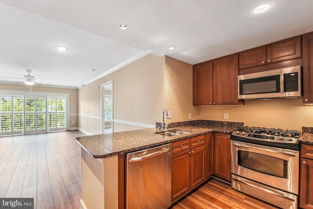 kitchen with ceiling fan, sink, kitchen peninsula, stainless steel appliances, and light wood-type flooring