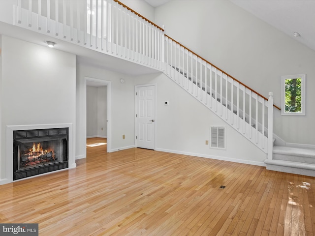 unfurnished living room featuring hardwood / wood-style floors and high vaulted ceiling