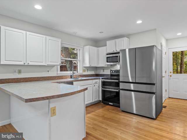 kitchen with a wealth of natural light, sink, appliances with stainless steel finishes, and white cabinets