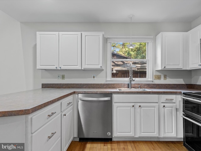 kitchen with appliances with stainless steel finishes, light hardwood / wood-style flooring, white cabinetry, and kitchen peninsula